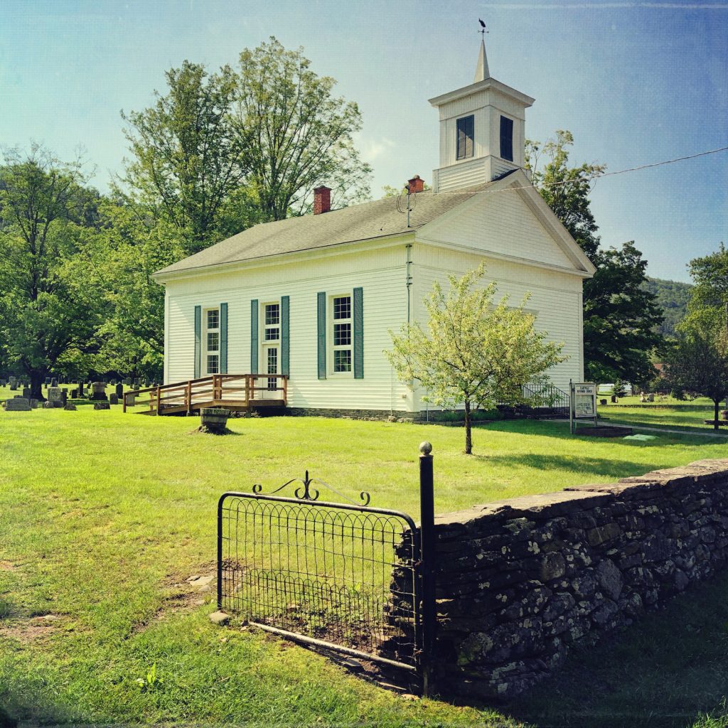 Side view of Claryville Church with stone wall and open gate